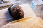 African man enjoys ozone facial steamer treatments at beauty spa salon